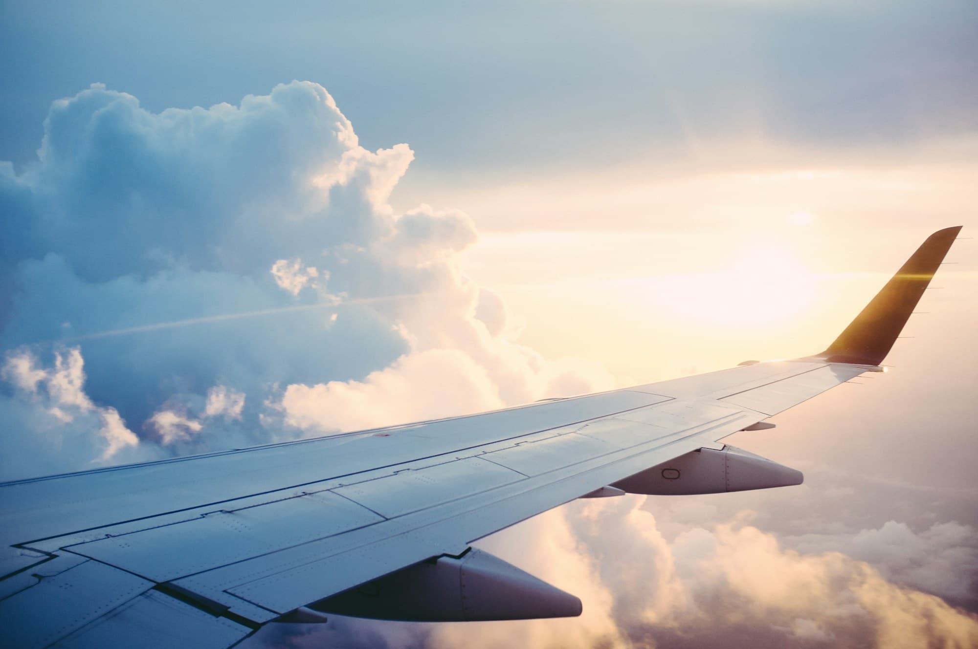 Airplane wing above the clouds in warm evening light